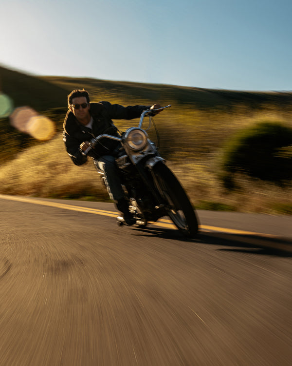 Man riding a motorcycle on a road with a blurred background